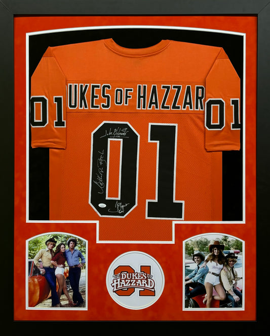 The Dukes of Hazzard "Luke Duke" Tom Wopat, "Daisy Duke" Catherine Bach, & "Bo Duke" John Schneider Hand Signed Autographed Custom Orange Jersey Framed & Suede Matted with JSA COA